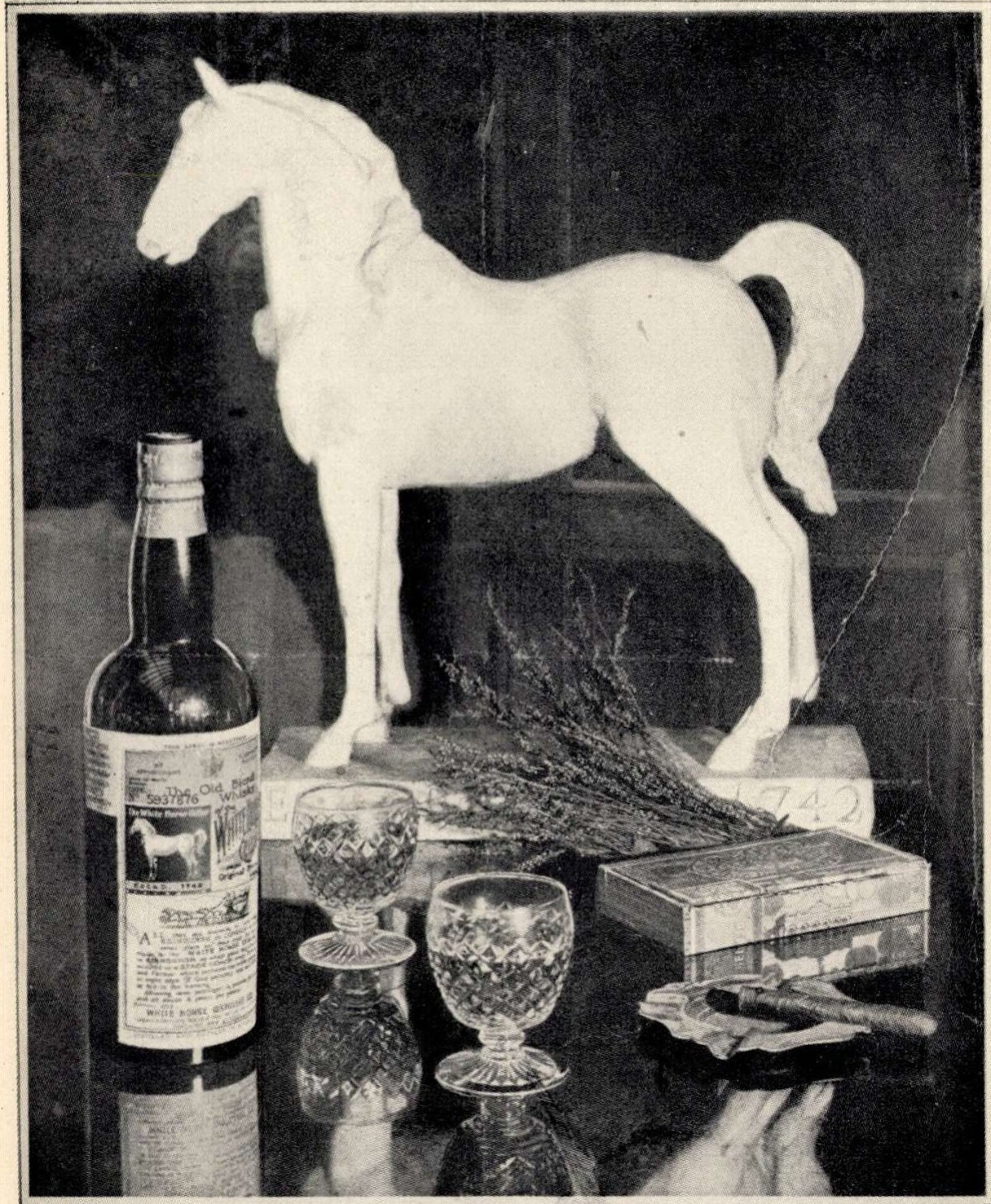 White Horse whiskyreklám: fehér ló szobra, üveg, poharak és szivarok.